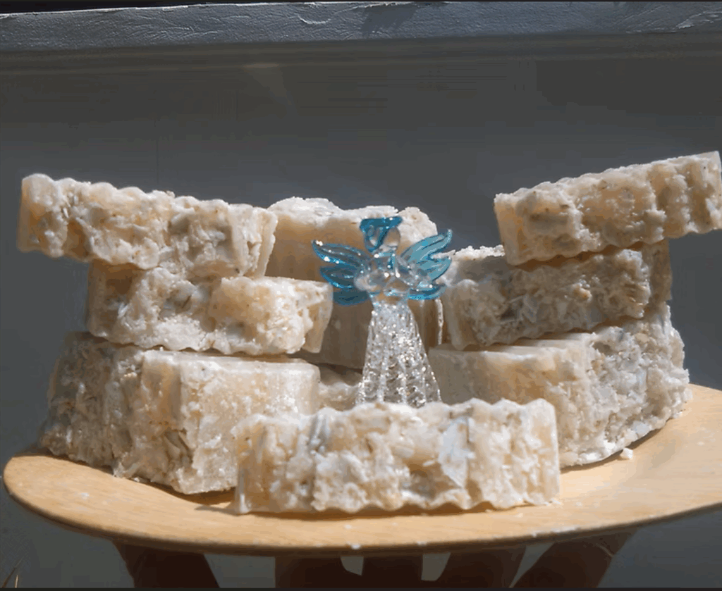 Bars of natural soap stacked next to an angel figurine